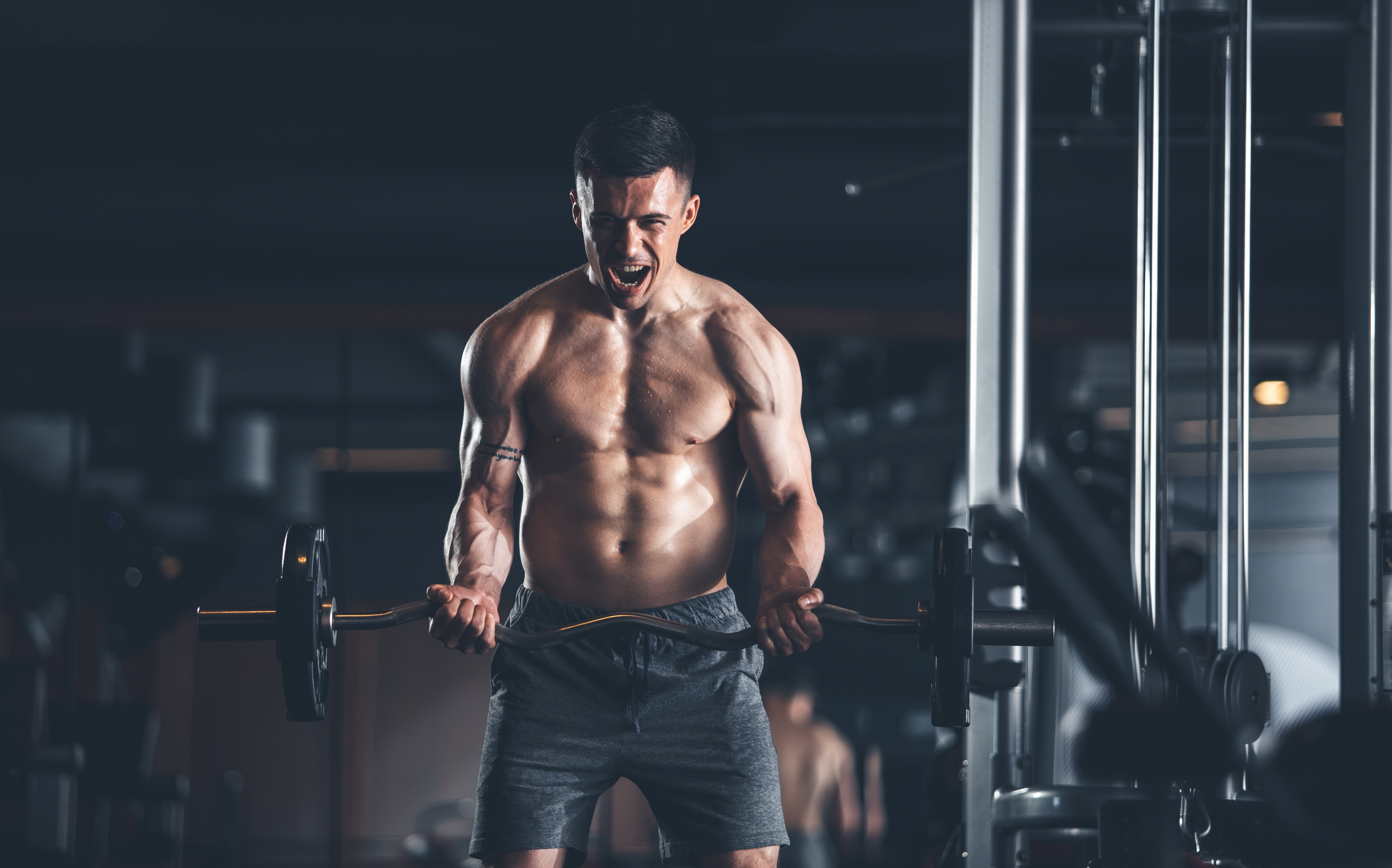 Hombre entrenando bíceps con barra en el gimnasio
